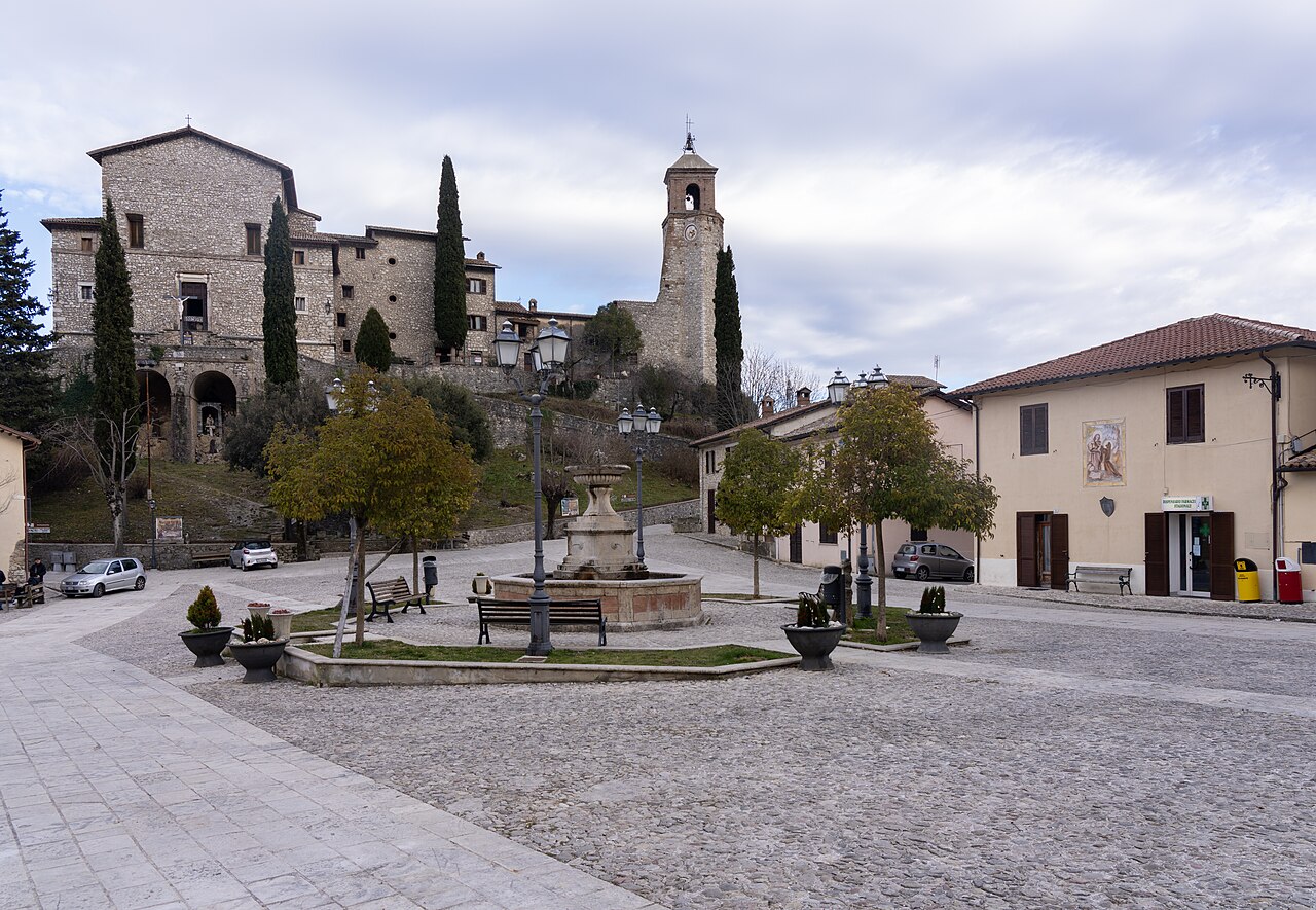 La piazza di Greccio con la fontana, il campanile e il centro storico medievale sullo sfondo